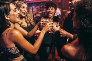 Gruppe von Freunden, die in einem Nachtclub feiern und anstoßen.