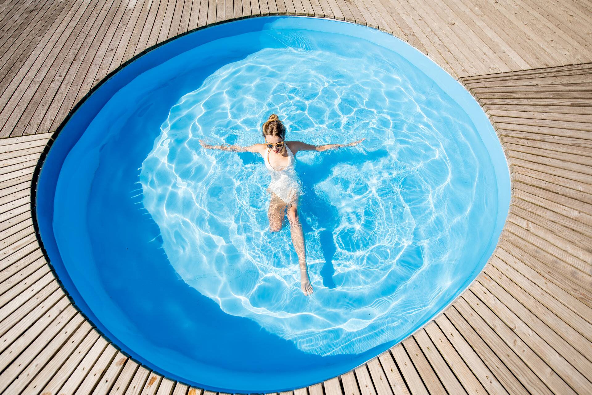 Draufsicht auf runden GFK Pool mit schwimmender Frau im Freien