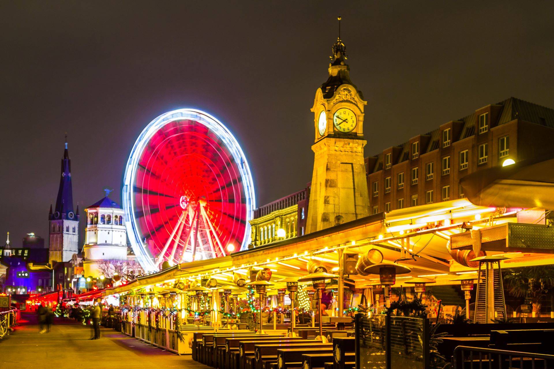 Beleuchtetes Riesenrad und historische Altstadt in Düsseldorf bei Nacht.