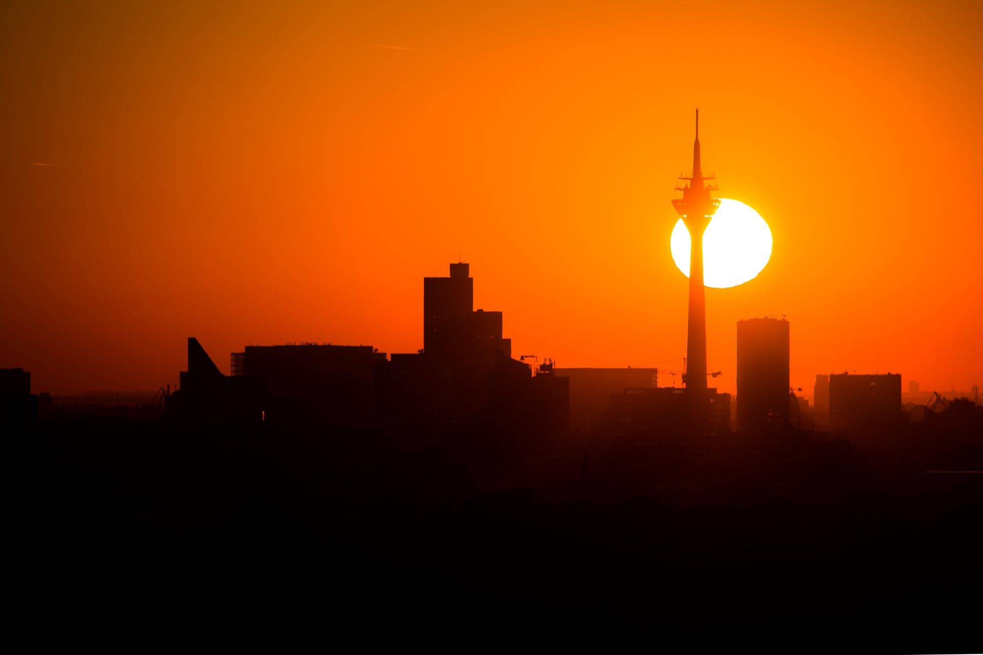 Der Rheinturm in Düsseldorf bei Sonnenuntergang mit Skyline.