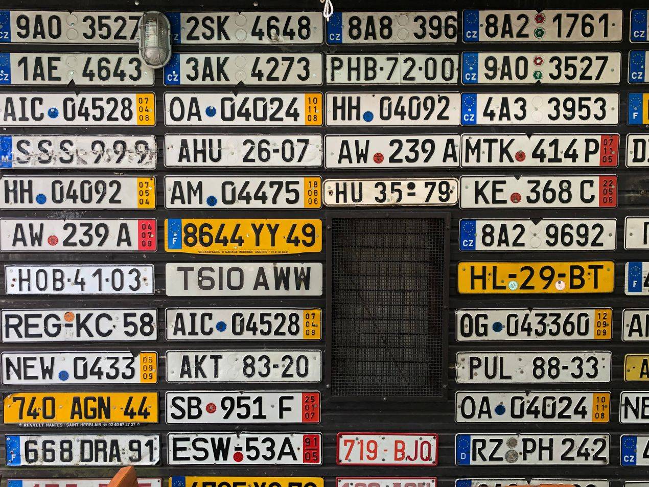 Wunschkennzeichen Mettmann im Kontext weltweiter Nummernschilder – Wand mit internationalen Kfz-Kennzeichen als Symbol für kreative Gestaltung