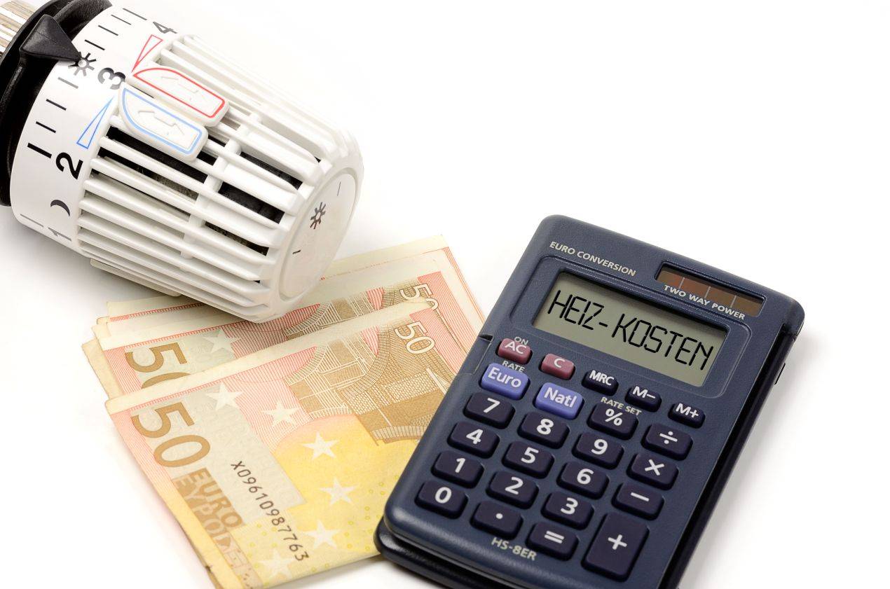 Heizkoerper-Thermostat, Geldscheine und Taschenrechner mit dem Wort „Heiz-Kosten“ – Symbolbild fuer Heizölpreise Düsseldorf und Sparpotenzial